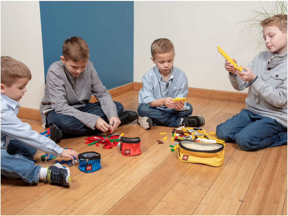 Cztery dzieci bawiące się LEGO z kolorowymi organizerami LEGO na klocki na drewnianej podłodze