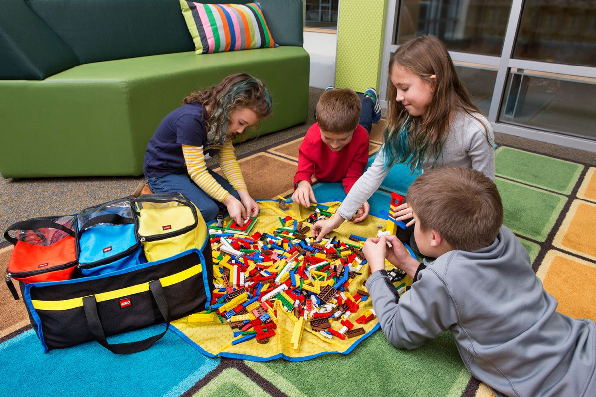 Dzieci bawiące się zestawem pojemników LEGO z matą na dywanie w kolorowym pokoju