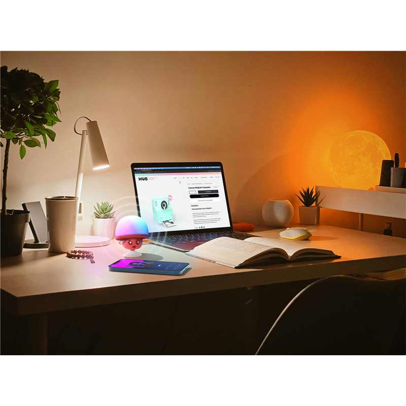 Świecący głośnik bezprzewodowy MOB w kształcie grzyba na biurku obok laptopa i książki