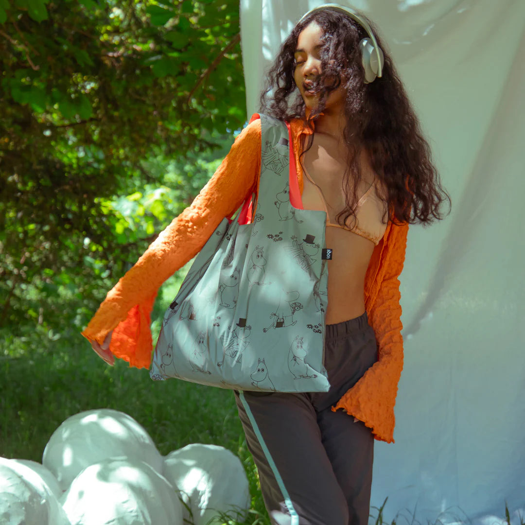 Kobieta nosząca torba LOQI Moomin odblaskowa na ramieniu w letnim otoczeniu