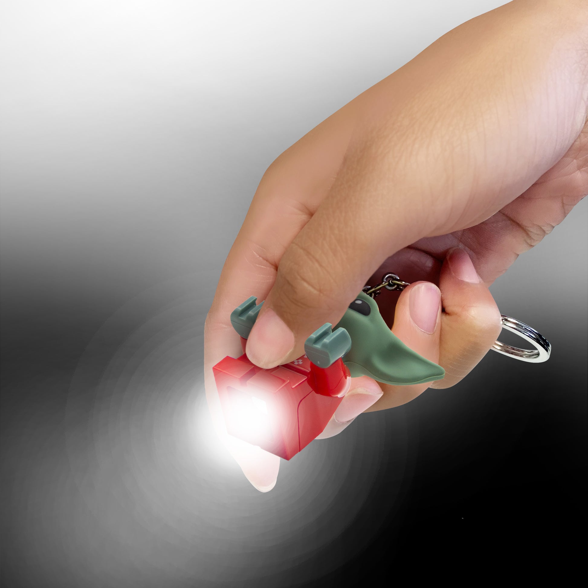 Brelok LEGO Star Wars Grogu z latarką trzymany w dłoni na czarnym i szarym tle