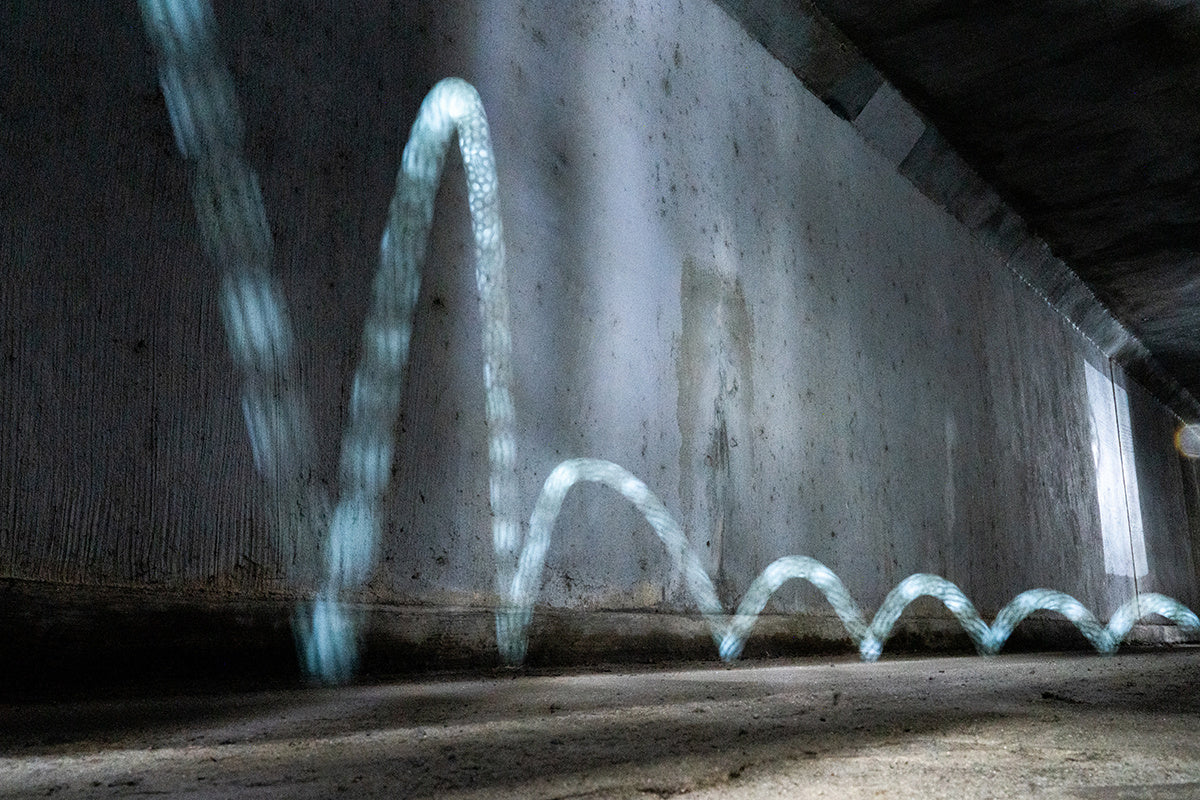 Świetlny ślad piłeczki Waboba Moonshine odbijającej się po betonowej powierzchni w tunelu