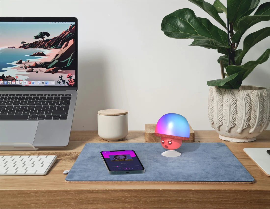Świecący głośnik bezprzewodowy MOB w kształcie grzyba na biurku obok laptopa i smartfona