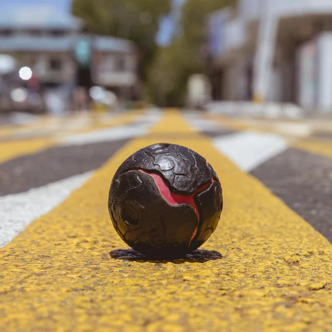 Czarna i czerwona piłeczka Waboba Lava na żółtej linii ulicy do zabawy na zewnątrz