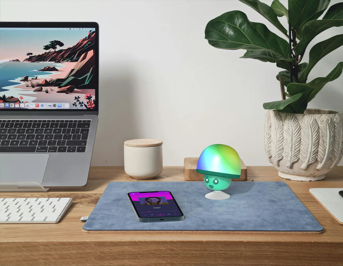 Świecący głośnik bezprzewodowy MOB w kształcie grzyba na biurku obok laptopa i smartfona