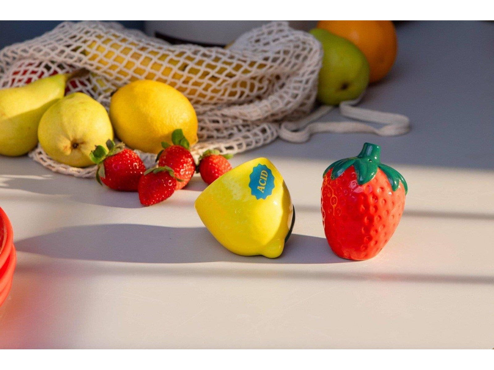 Solniczka i pieprzniczka truskawka cytryna od DOIY na białym stole z owocami w tle