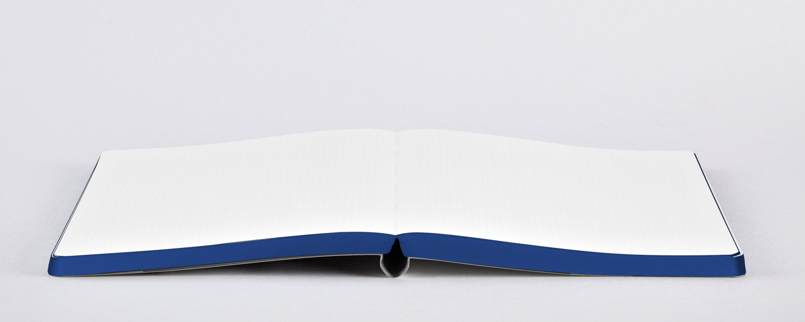 Otwarty notatnik graficzny A5 z białymi kartkami i niebieską oprawą na szarym tle