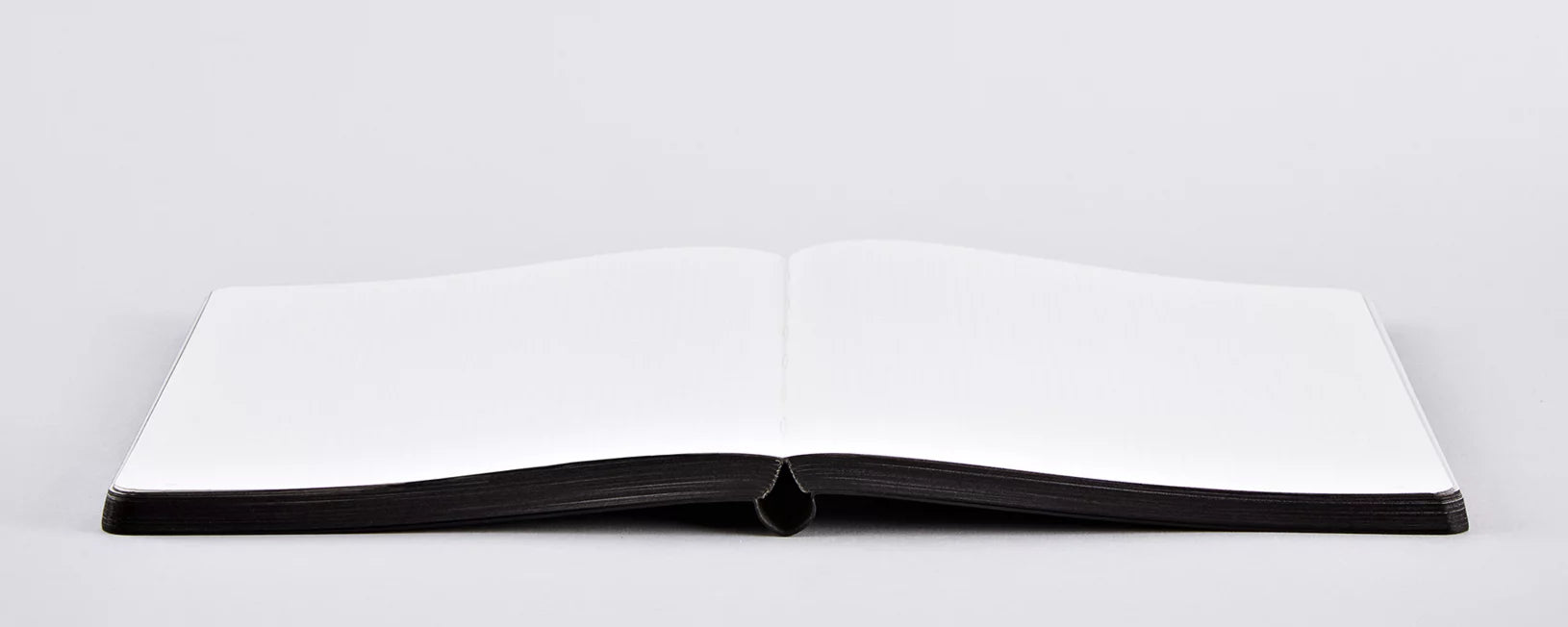 Notatnik Voyager L czarny otwarty na biały pusty papier na szarym tle