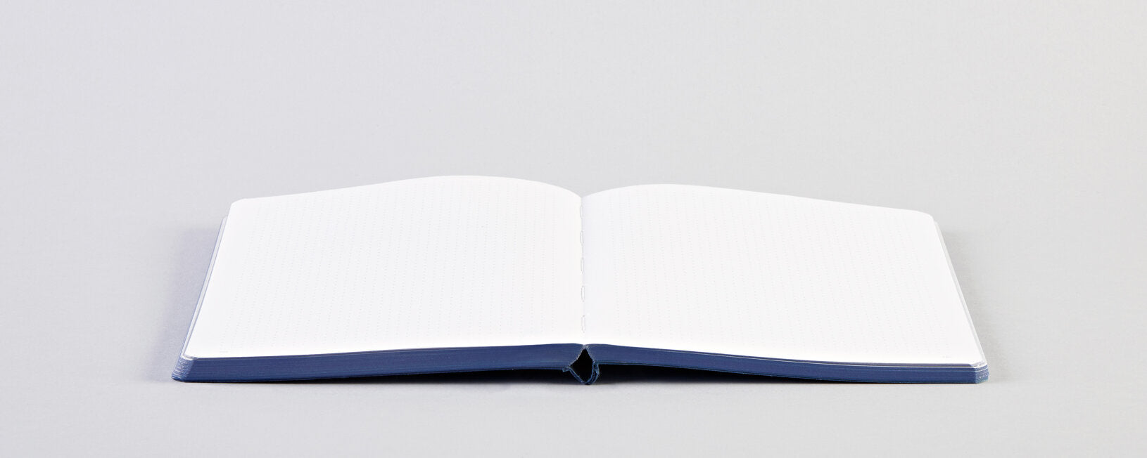 Otwarty notatnik Surface M Transcendence z czystymi białymi stronami na szarym tle