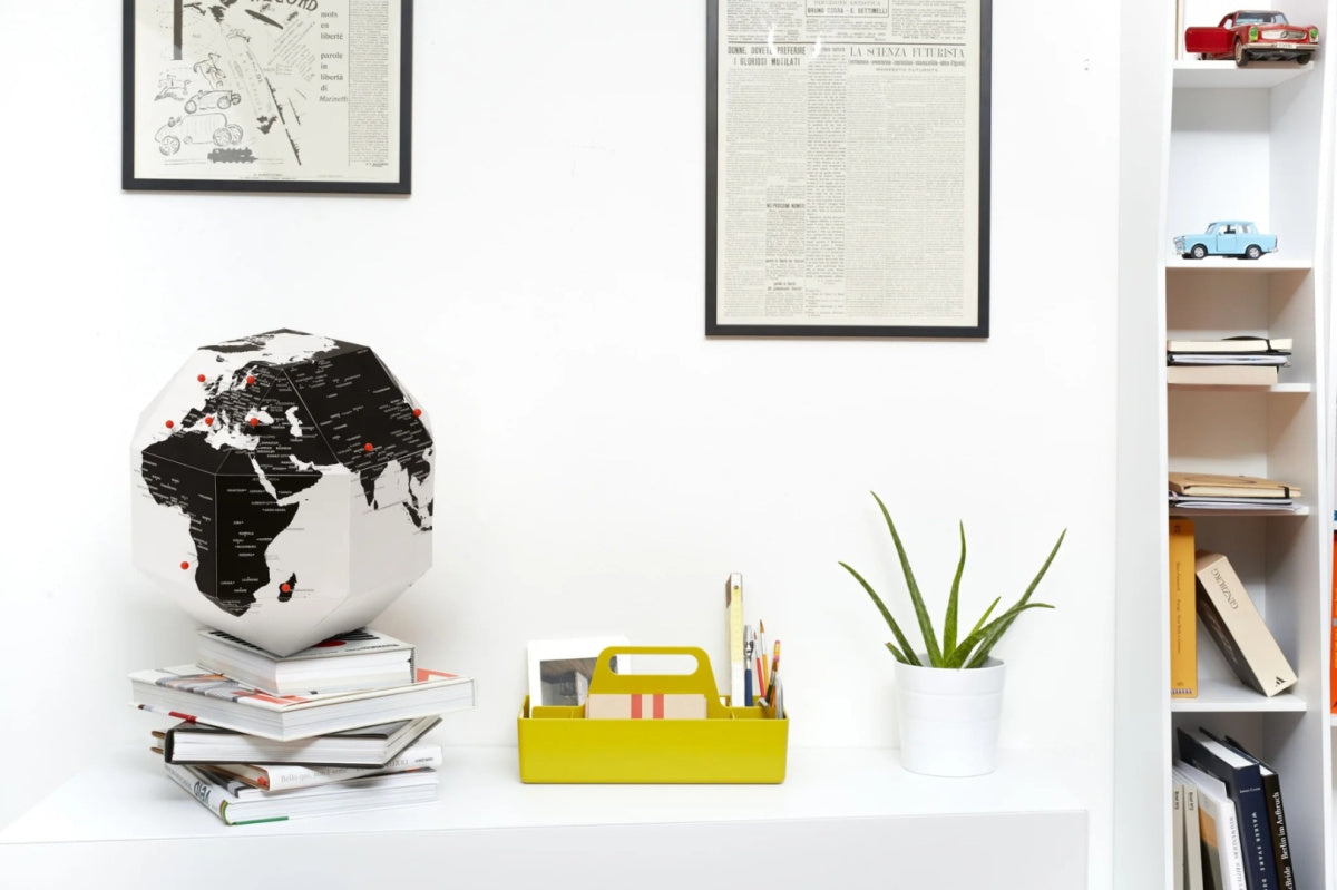 Nowoczesny globus z pinezkami na stosie książek na białym biurku w minimalistycznym wnętrzu