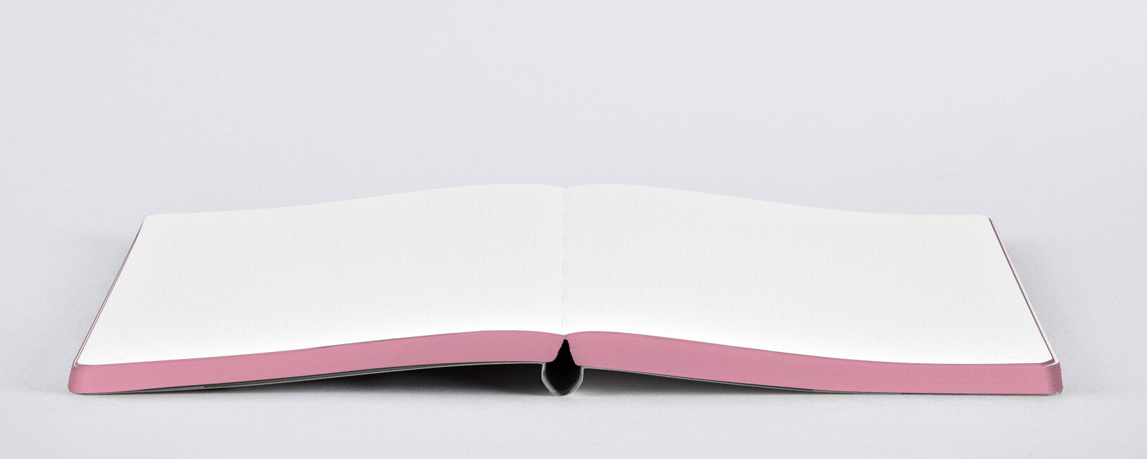 Otwarty notatnik Graphic L Sweet Joe z białymi kartkami i różową oprawą na białym tle