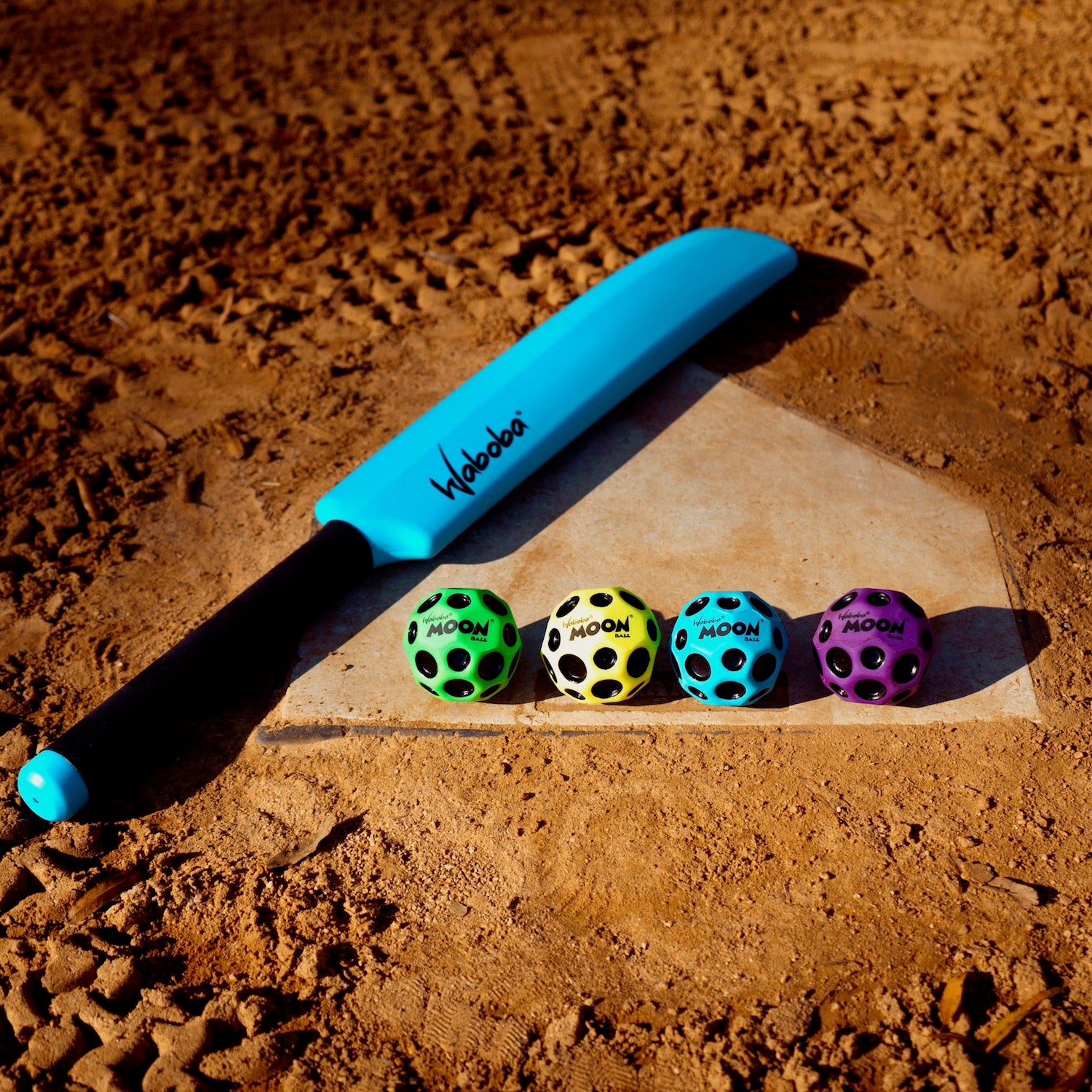 Zestaw do gry Waboba Moon Cracket z niebieską rakietą i czterema kolorowymi piłkami na piasku