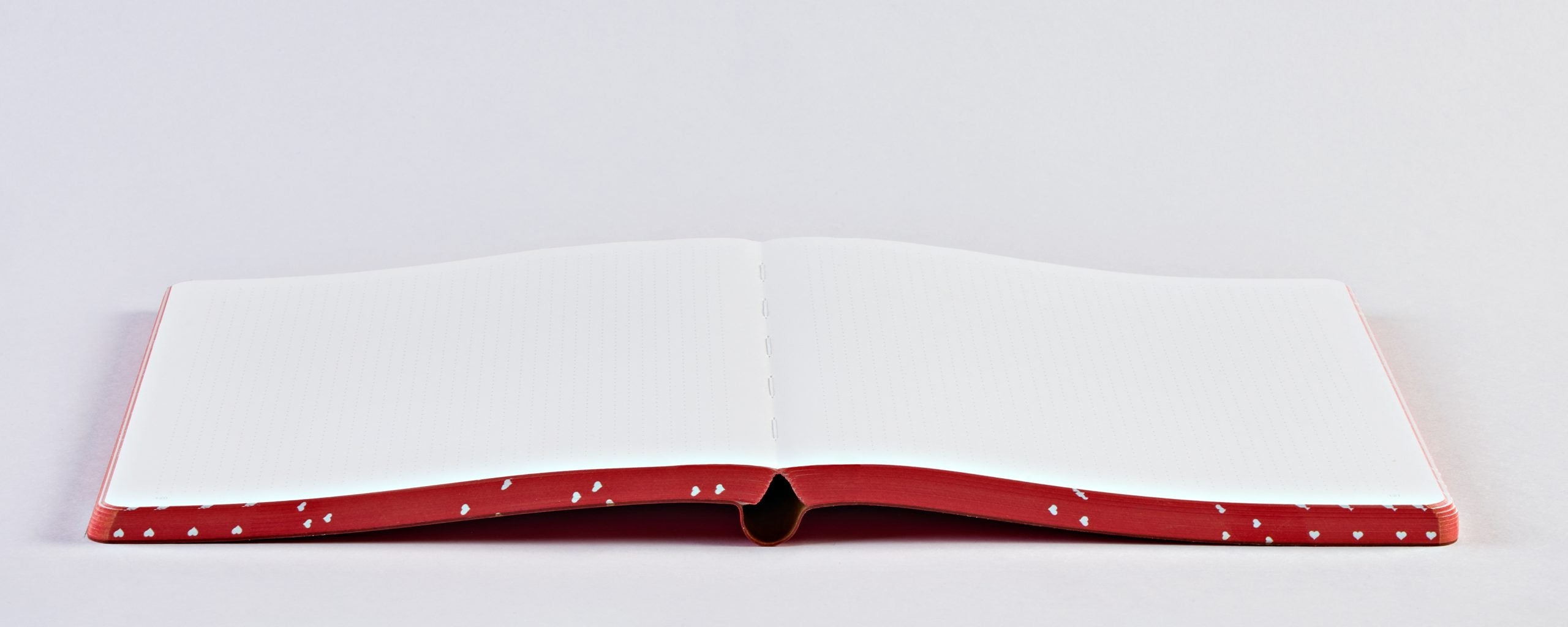 Otwarty notatnik graficzny Heart Core z czerwonymi bokami i białymi kartkami na płaskiej powierzchni