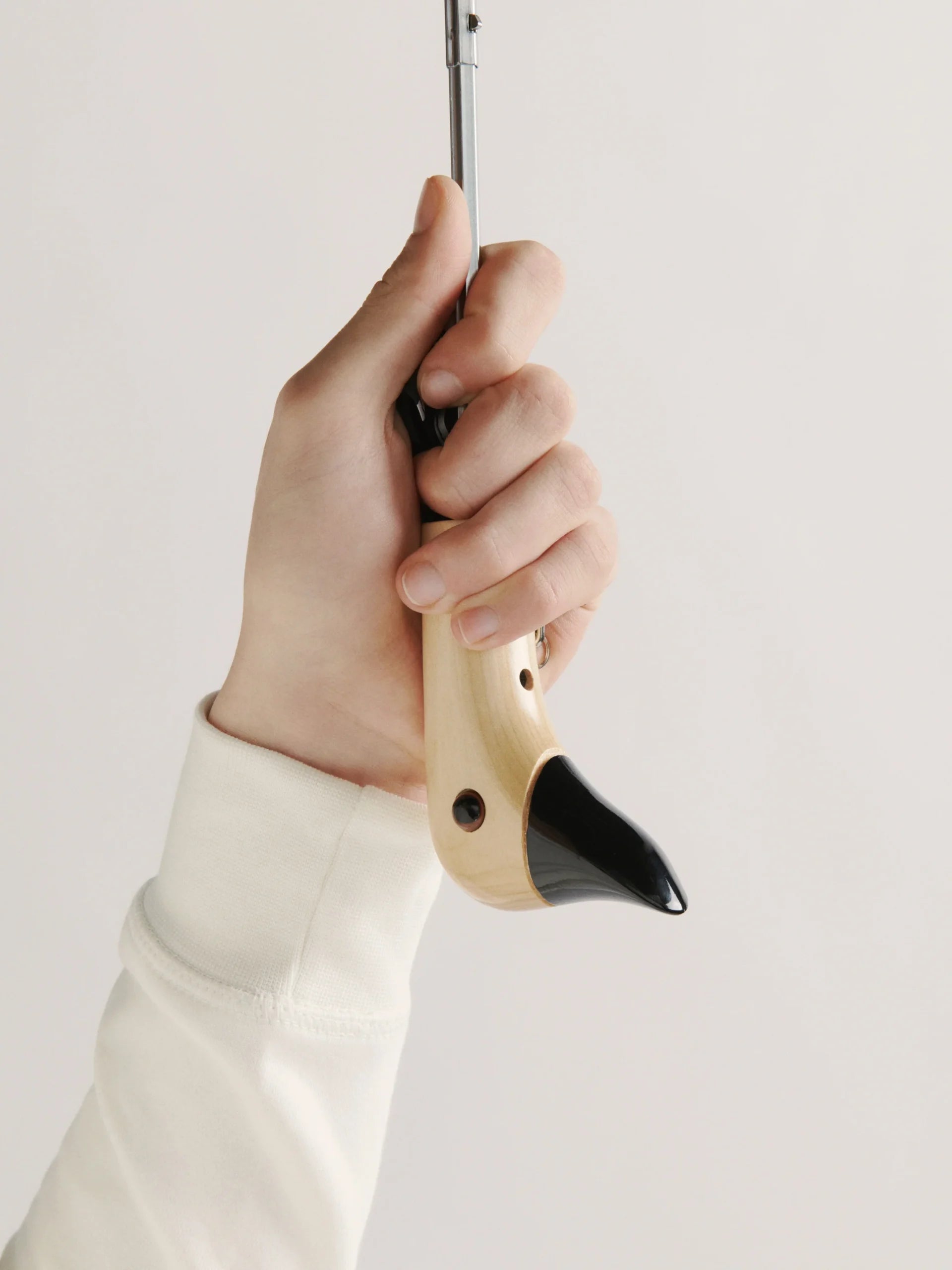 Ręka trzymająca czarną parasolkę z drewnianą rączką marki WABOBA AB