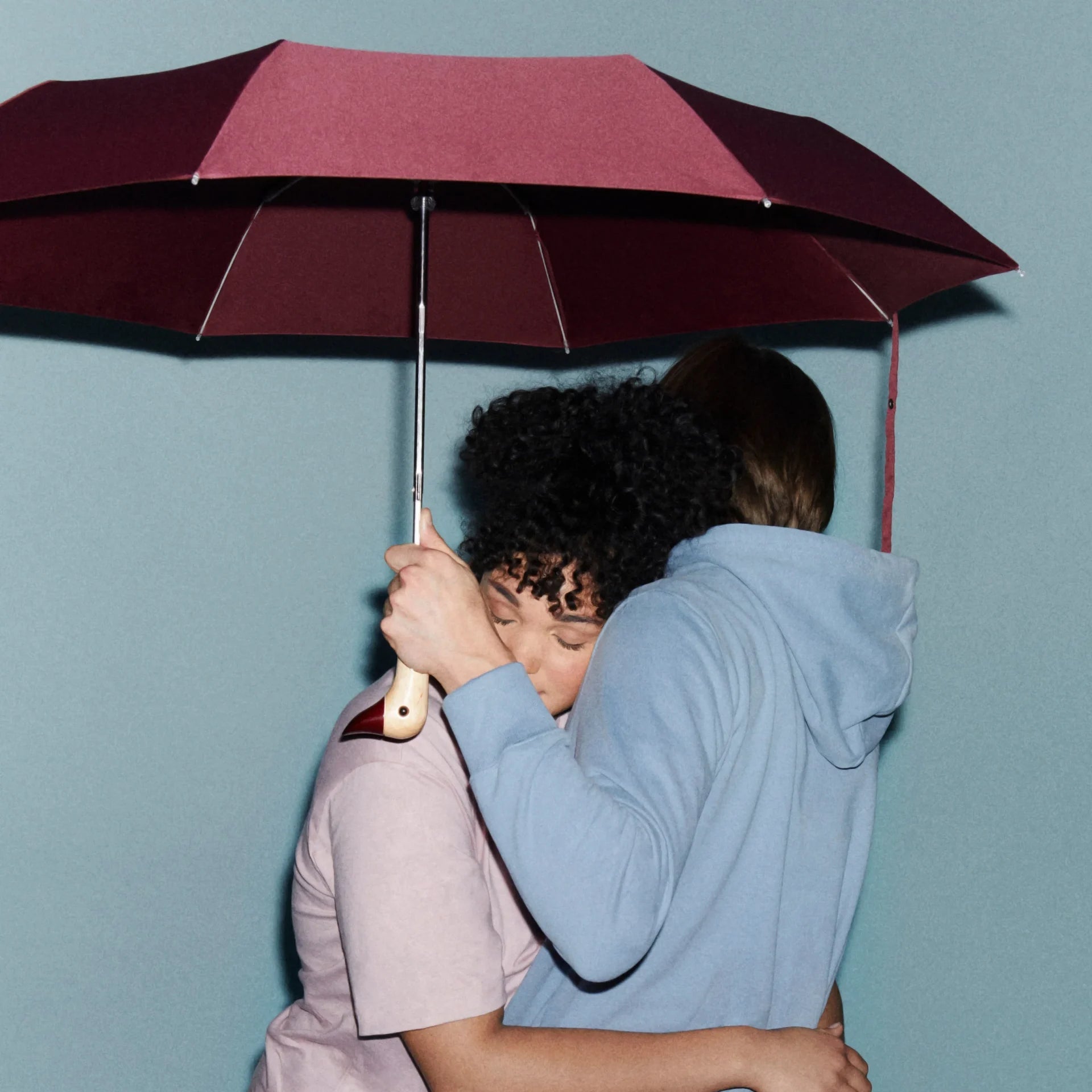 Parasolka z rączką w kształcie kaczki trzymana przez parę pod bordowym parasolem