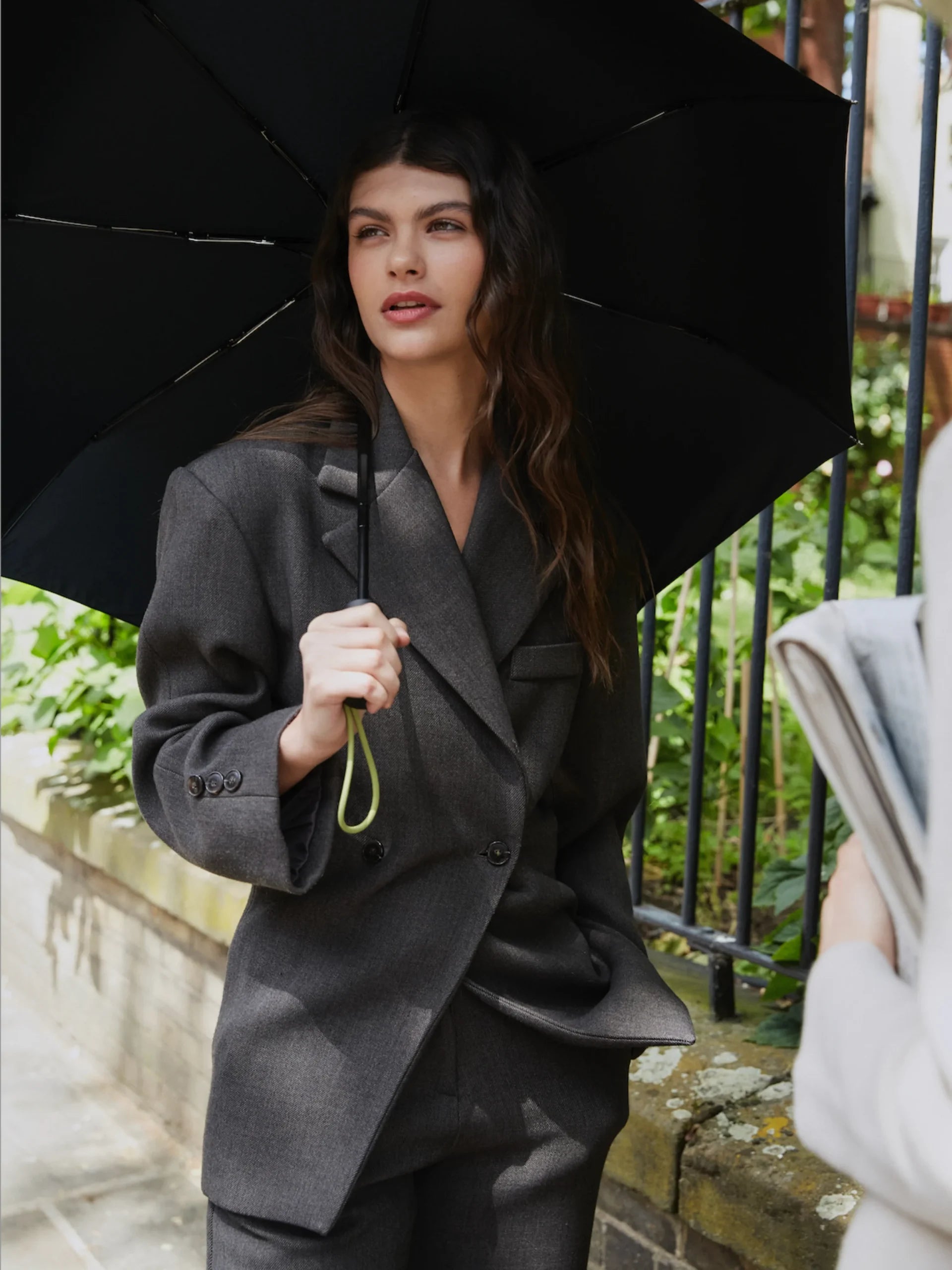 Kobieta trzyma parasolkę automatyczna czarna marki LOQI podczas spaceru w deszczu