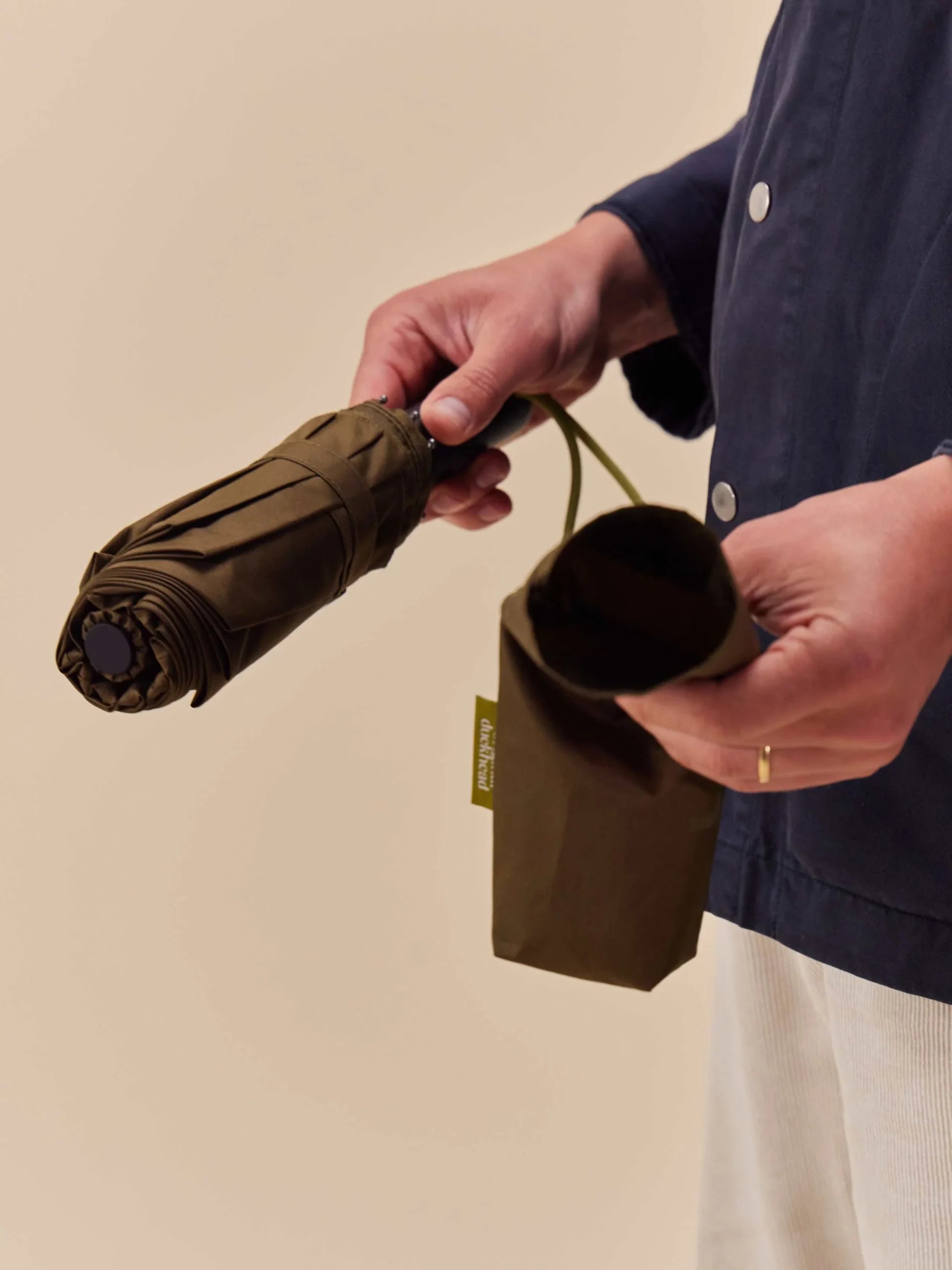 LOQI parasolka automatyczna ciemna oliwkowa składana z pokrowcem w rękach osoby