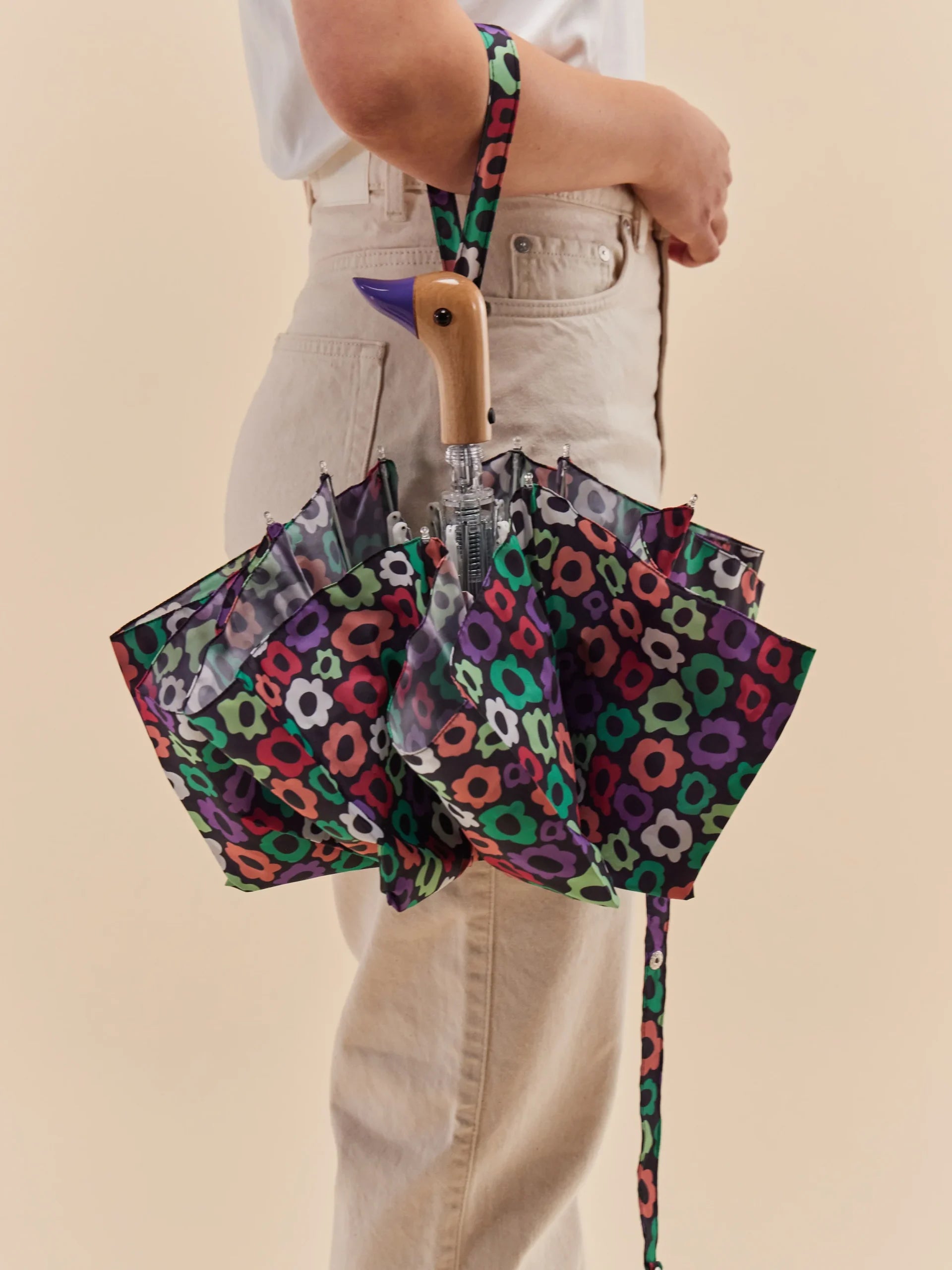 Parasolka z rączką w kształcie kaczki z kolorowym kwiatowym wzorem, trzymana przez osobę