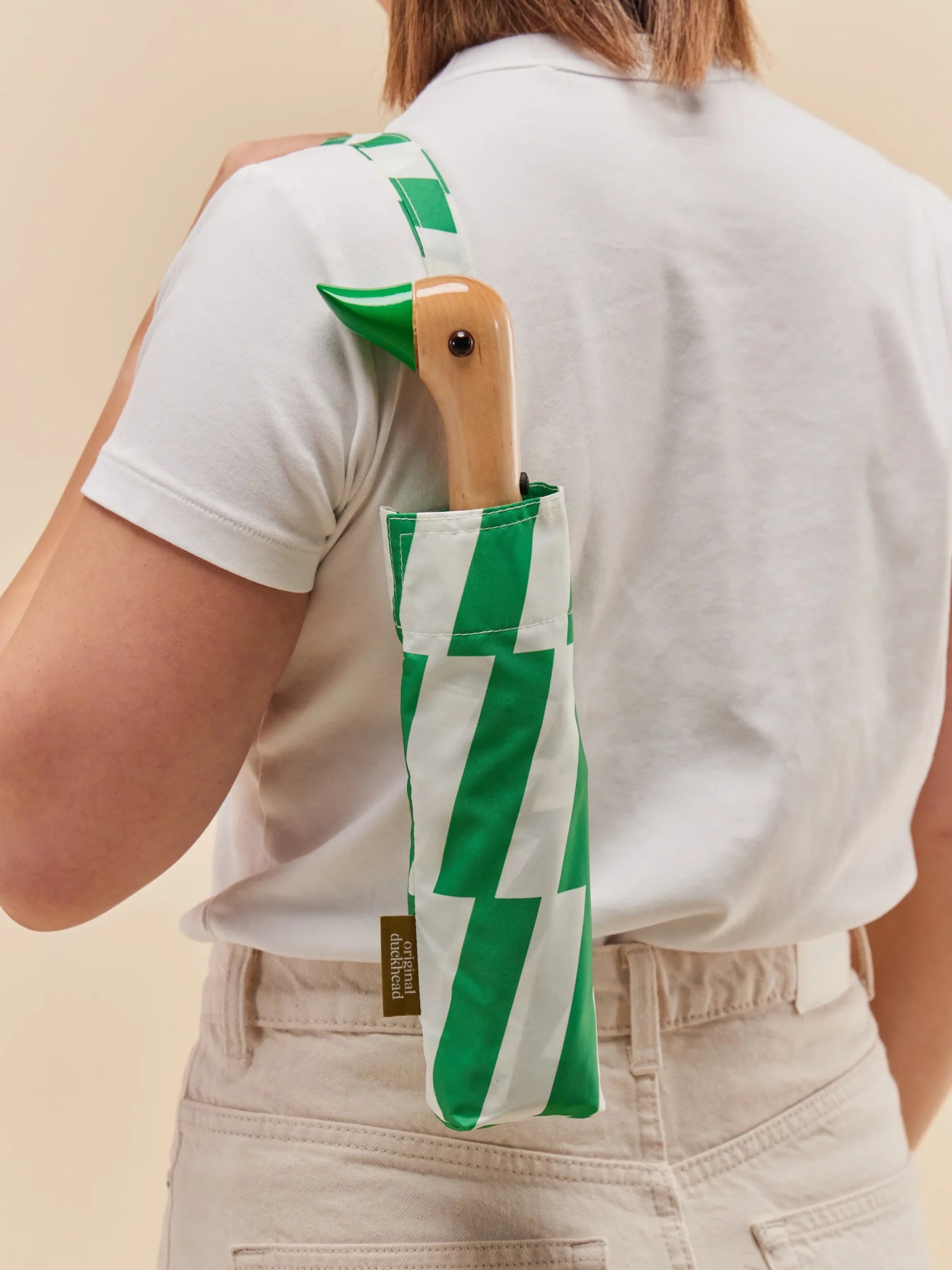 Parasolka z rączką w kształcie kaczki w pokrowcu w zielone i białe paski, noszona na ramieniu