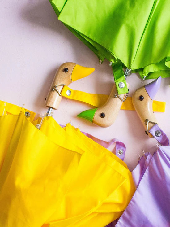 Żółta parasolka z rączką kaczka na tle zielonej i fioletowej parasolki z drewnianymi uchwytami