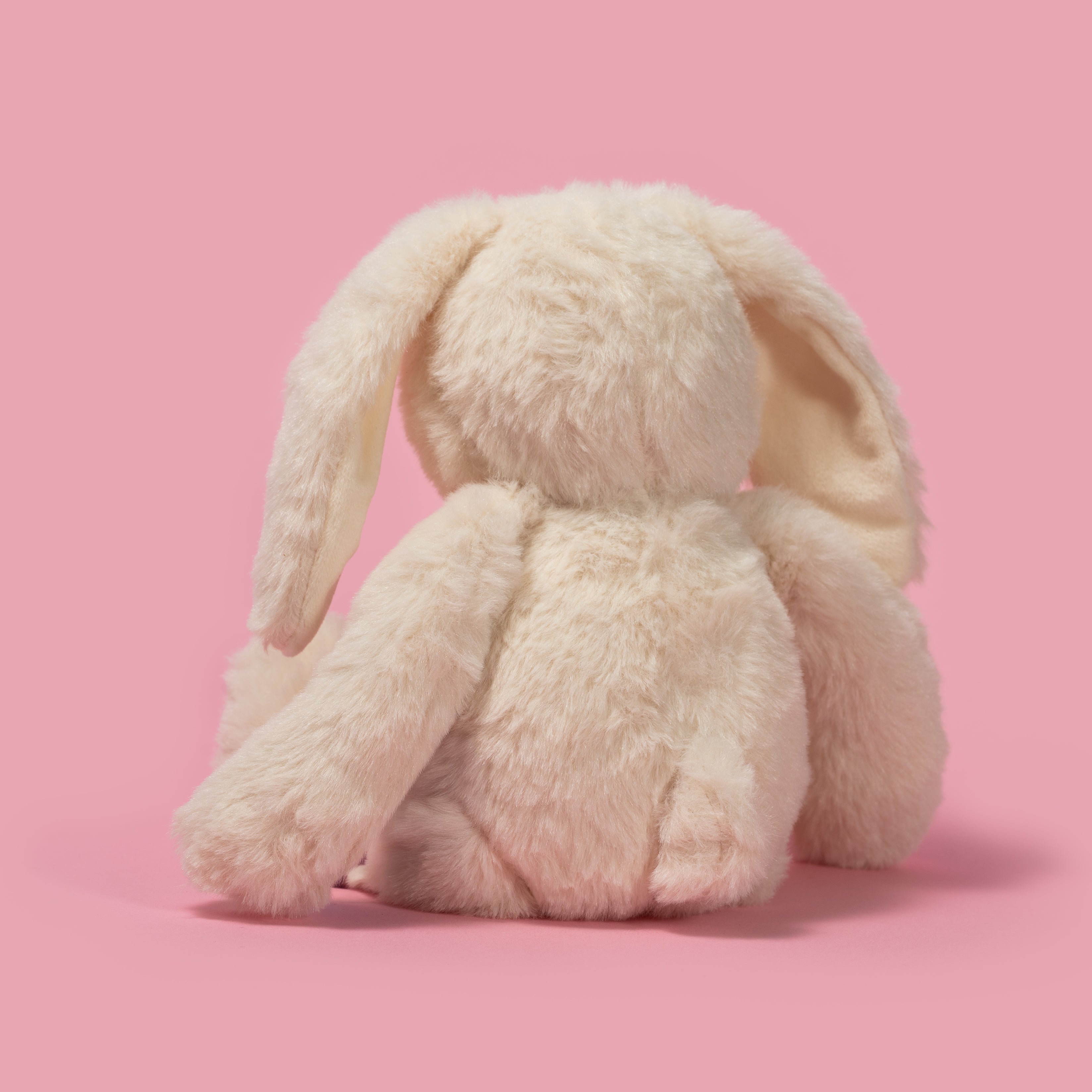 Pluszak króliczek Wild Planet w jasnym kolorze siedzący na różowym tle tyłem