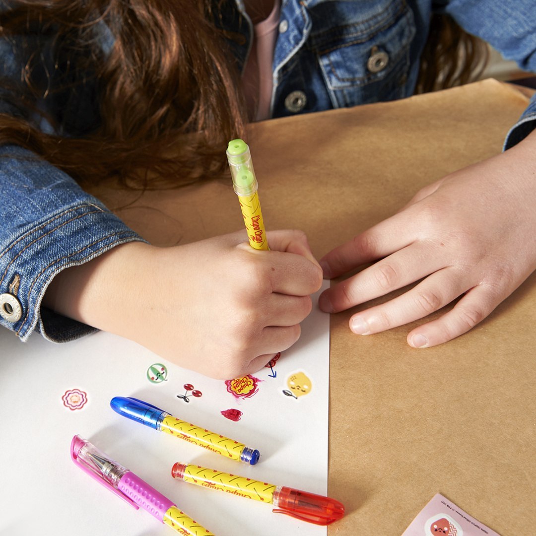 Dziecko rysujące flamastrami zapachowymi Chupa Chups na białej kartce papieru