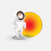 Lampka projekcyjna astronauta w białym skafandrze stojąca na księżycowej powierzchni z ciepłym światłem