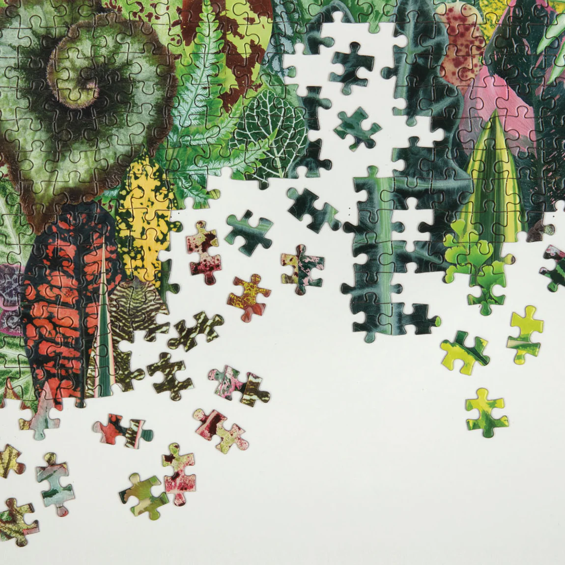 Częściowo ułożone puzzle z motywem roślin od Galison z kolorowymi liśćmi i zielonym tłem