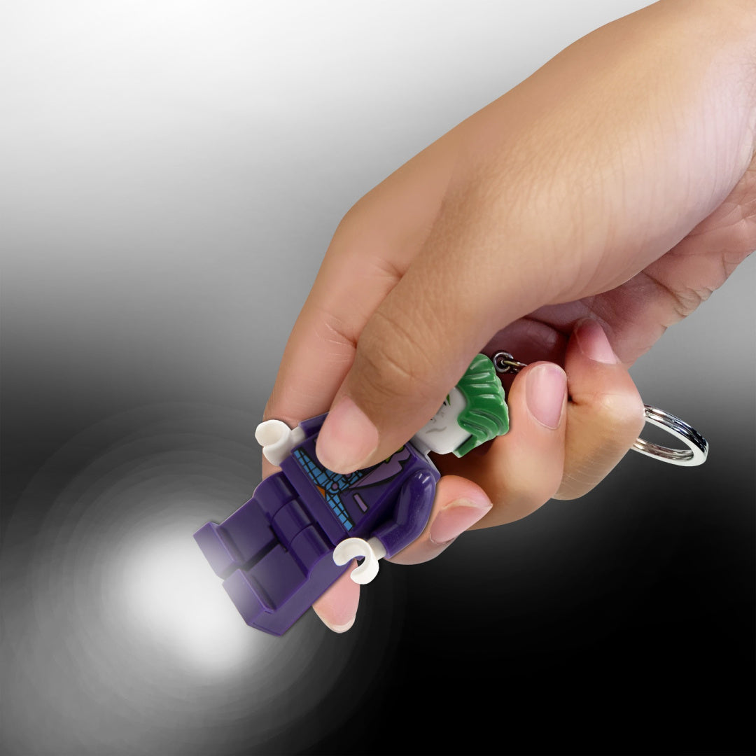Brelok LEGO Joker z latarką trzymany w dłoni emitujący światło z latarki