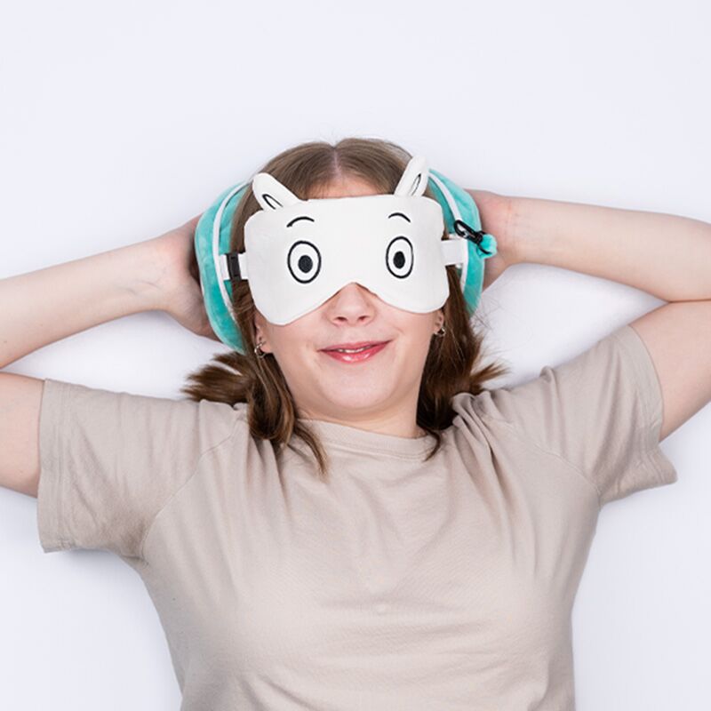 Pluszowa poduszka podróżna Moomin na uszy oraz opaska na oczy w stylu Moomin na twarzy uśmiechniętej dziewczyny