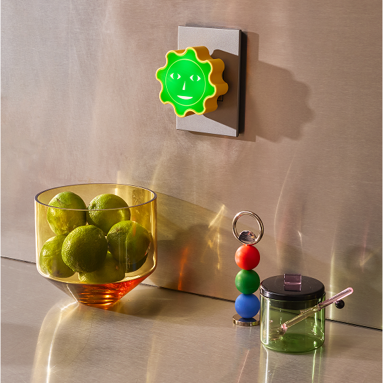 Lampka nocna dla dzieci Areaware w kształcie zielonego słońca zamontowana na ścianie w nowoczesnym wnętrzu