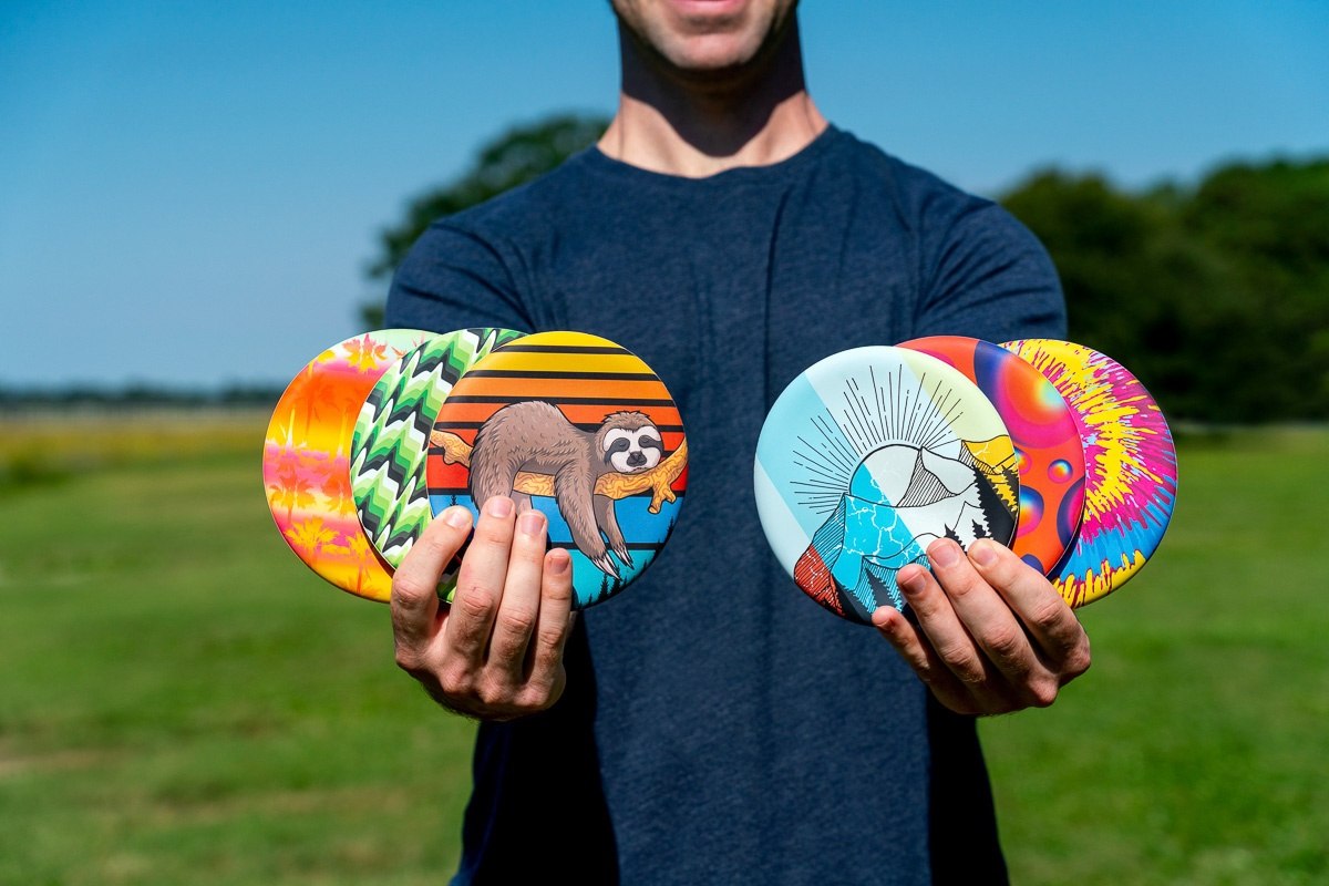 Frisbee Waboba Wingman z kolorowymi wzorami trzymane przez osobę na tle zielonego pola