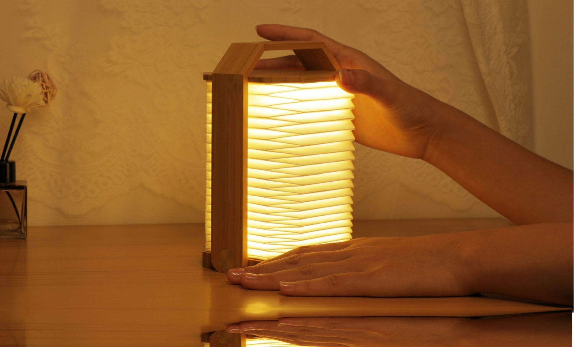 Inteligentna lampa origami orzech świecąca ciepłym światłem na drewnianym stole z rękami