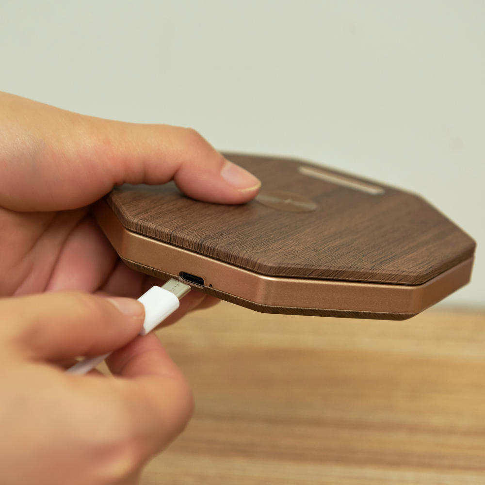 Gingko Design sześciokątna lampa stołowa z drewnianym wykończeniem podczas podłączania kabla USB