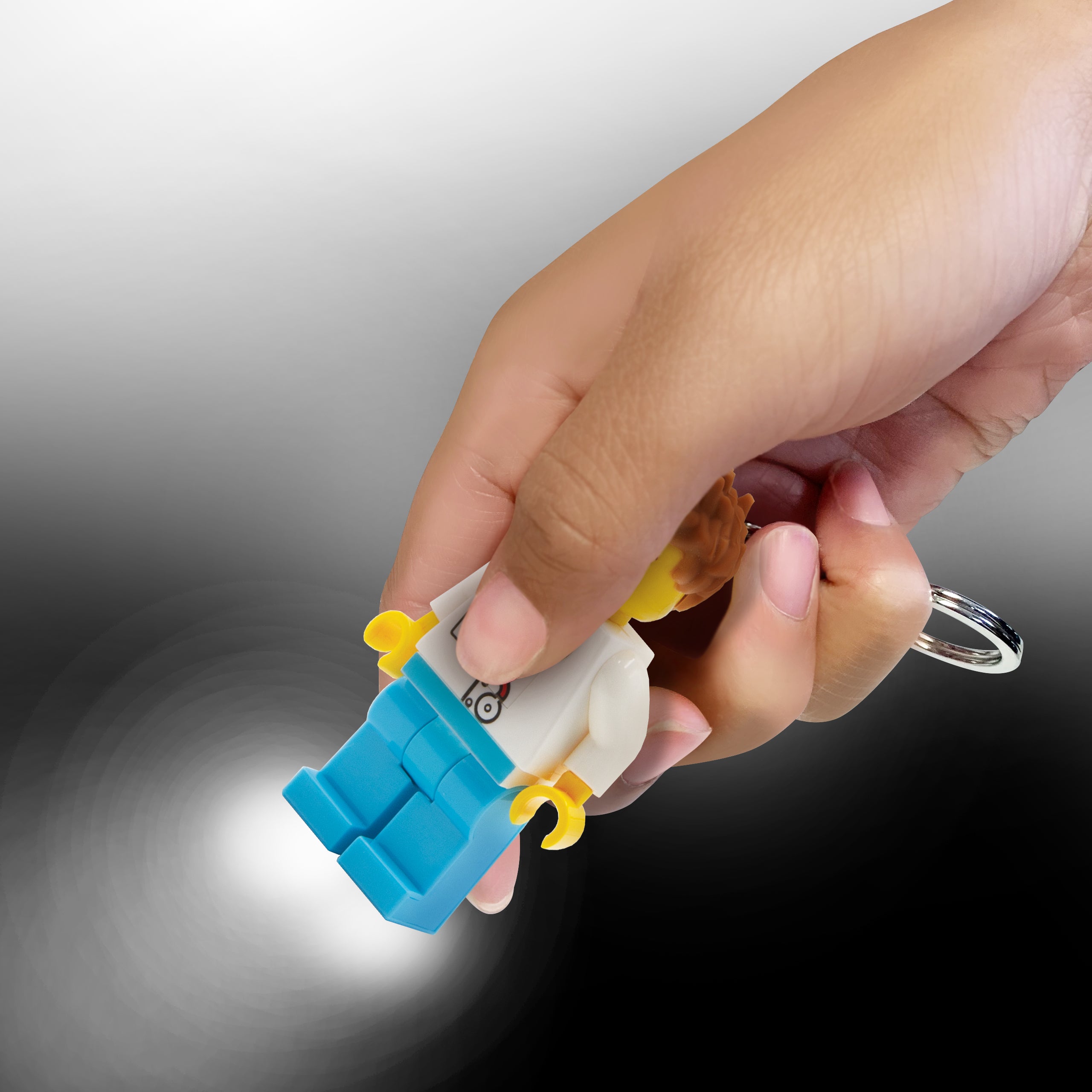 Brelok LEGO lekarz z latarką trzymany w dłoni z wysuwaną świecącą latarką