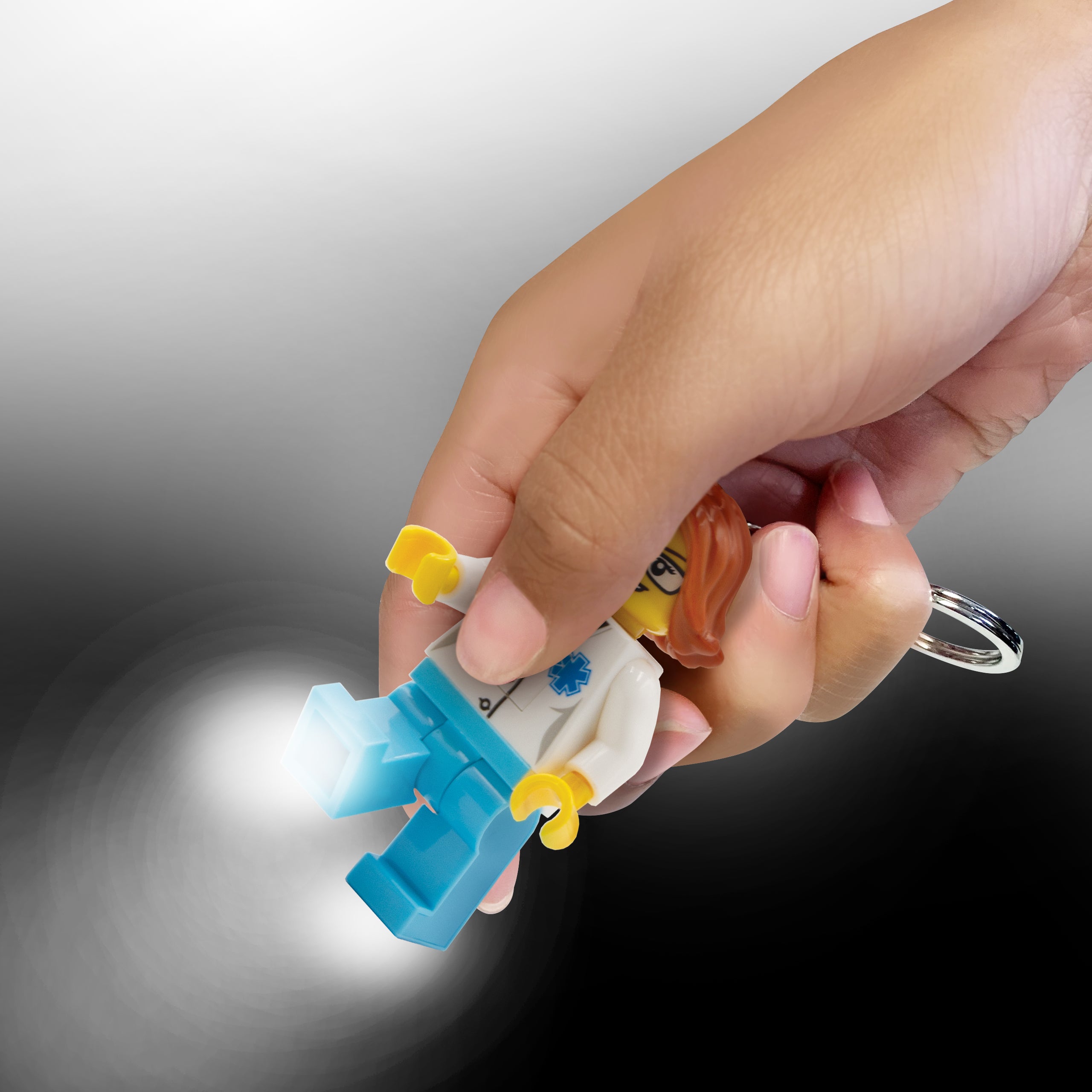 brelok lego latarka lekarka w dłoni z podświetlanymi niebieskimi nogami i metalowym kółkiem
