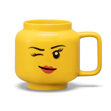 Taza LEGO cabeza grande niña de color amarillo con cara sonriente y ojo cerrado