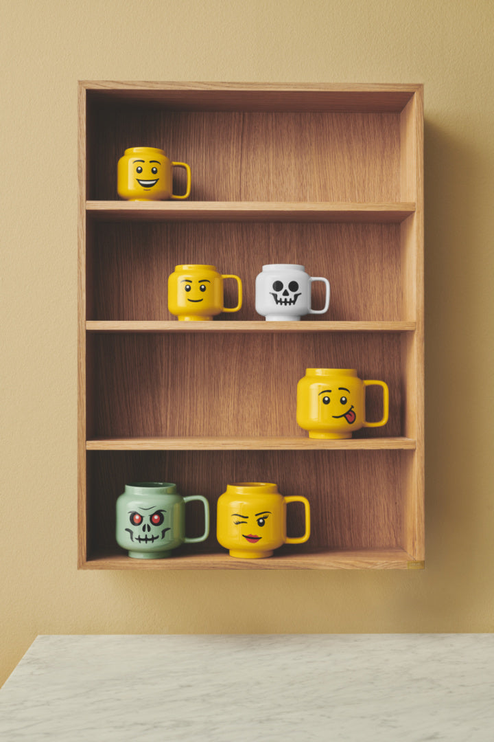 kubek ceramiczny LEGO Szkieletor i kolorowe kubki z uśmiechami na drewnianej półce