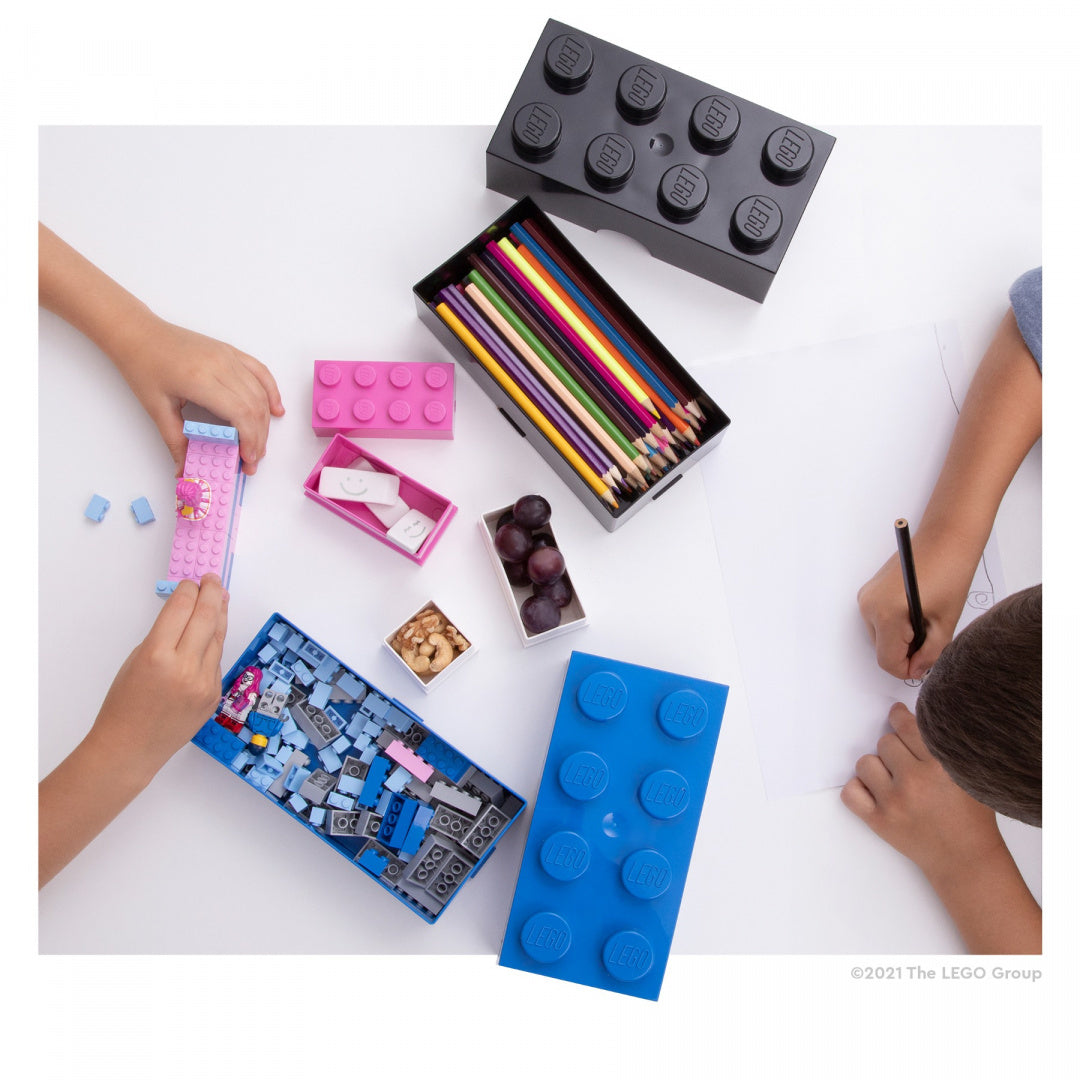 Lunchbox LEGO niebieski w kształcie klocka z ołówkami i zabawkami na białym tle