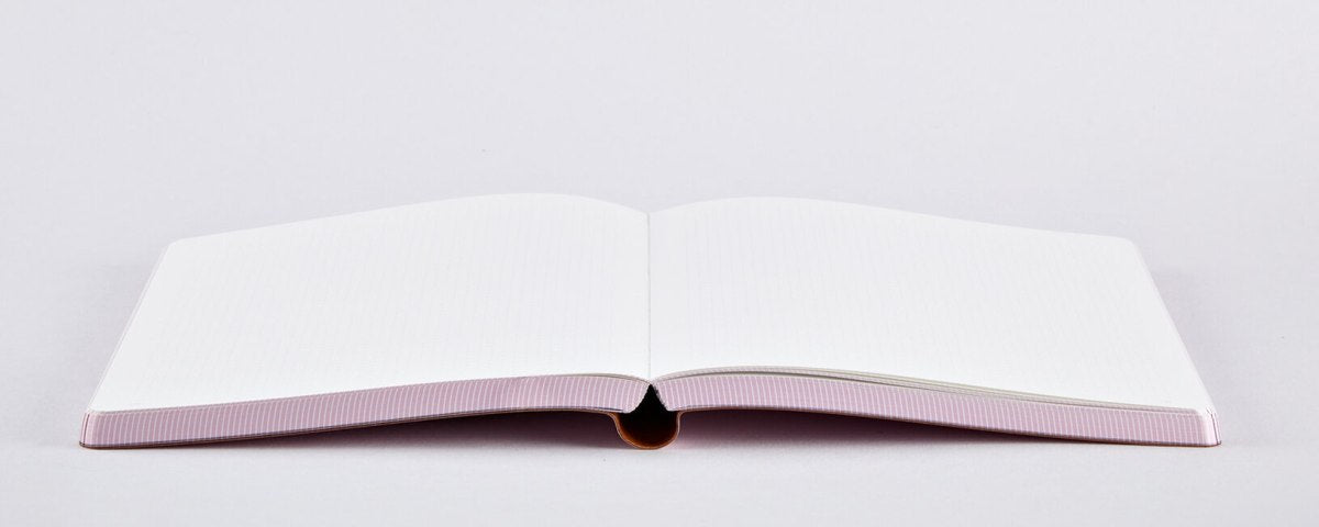 Otwarty notatnik graficzny OX z pustymi białymi stronami leżący na jasnym tle