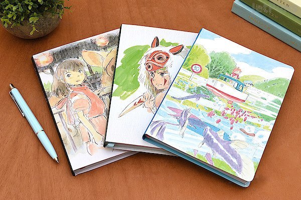 notatnik Spirited Away z ilustracjami postaci z filmu Studio Ghibli na drewnianym stole