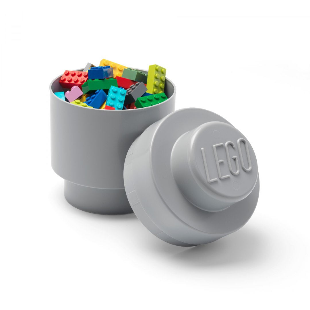 Szary okrągły pojemnik LEGO wypełniony kolorowymi klockami na białym tle