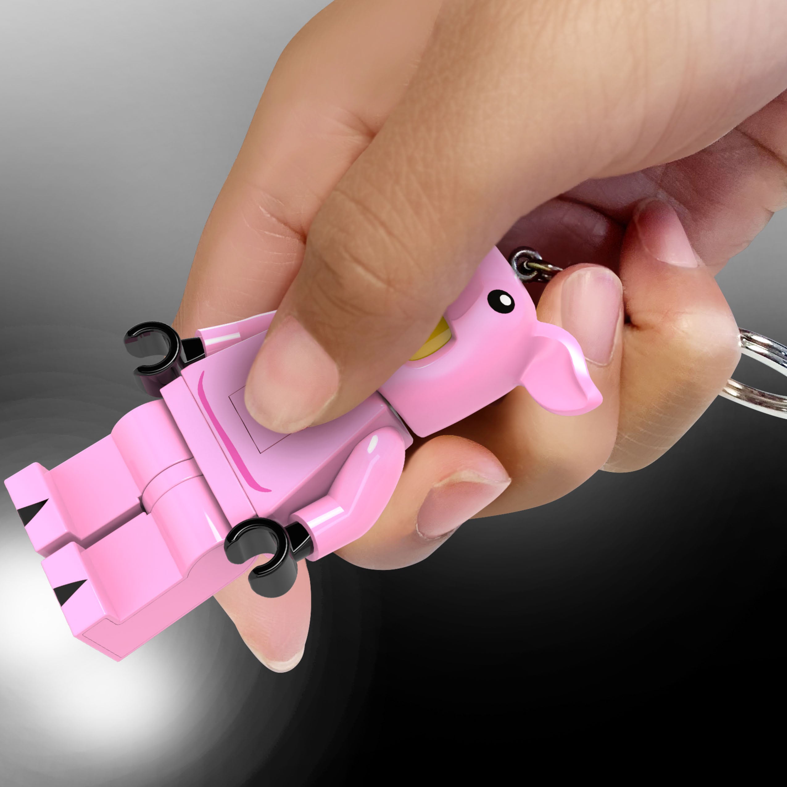 Ręka trzyma brelok LEGO minifigurka świnka różowa z czarnym kółkiem do kluczy
