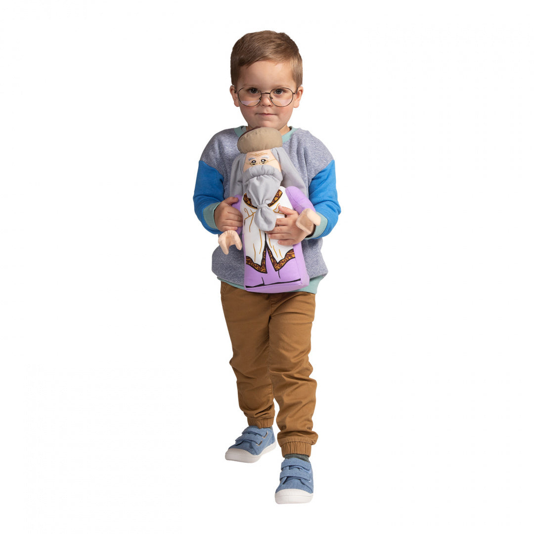Chłopiec trzymający pluszak Dumbledore LEGO Harry Potter w fioletowym płaszczu na białym tle