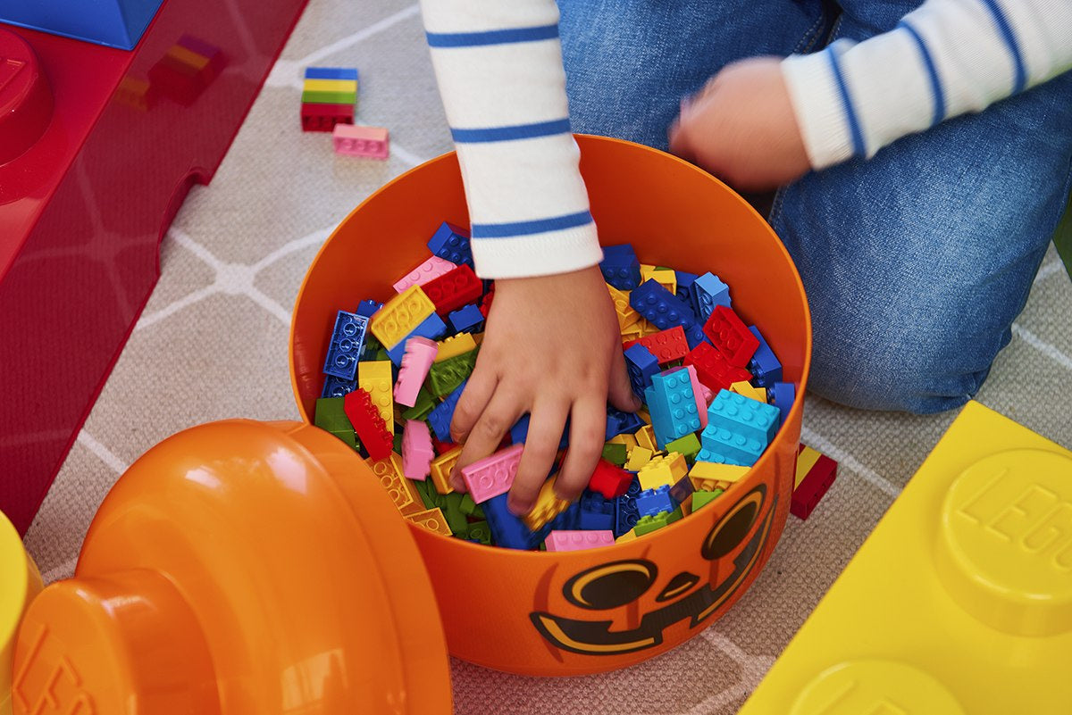 Dziecko sięgające do pojemnika LEGO dynia wypełnionego kolorowymi klockami LEGO