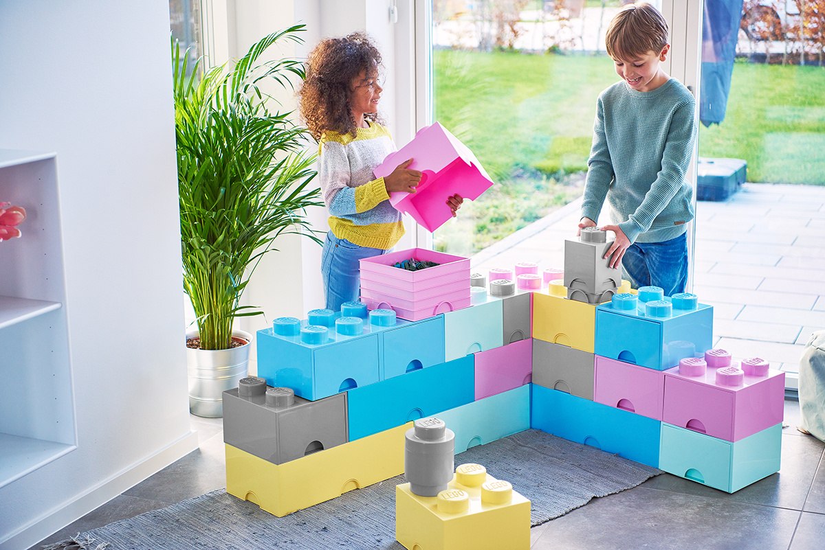 Dzieci bawiące się dużymi klockami i pojemnik LEGO jasnoniebieski w jasnym pokoju z widokiem na ogród