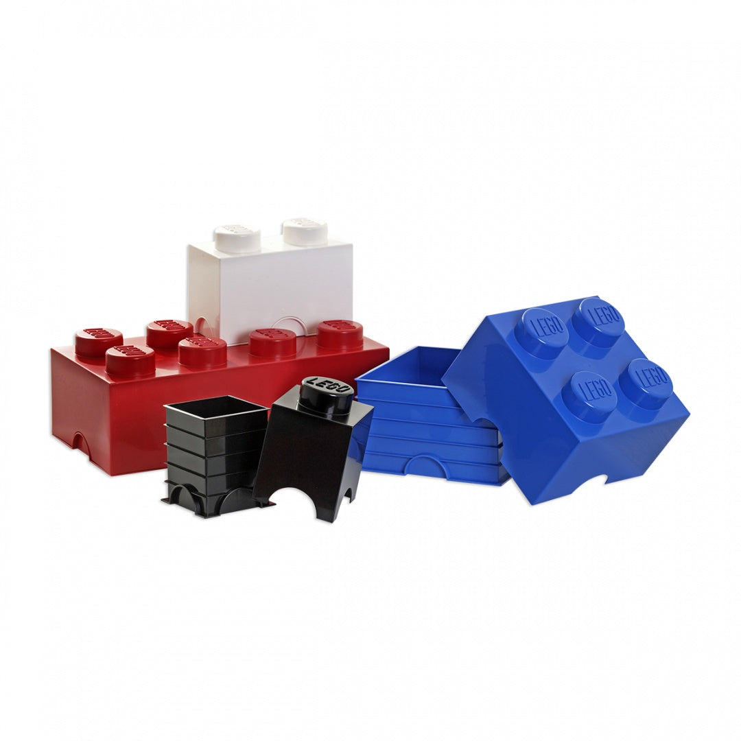 Pojemnik LEGO biały w kształcie klocka obok czerwonych, niebieskich i czarnych pojemników LEGO