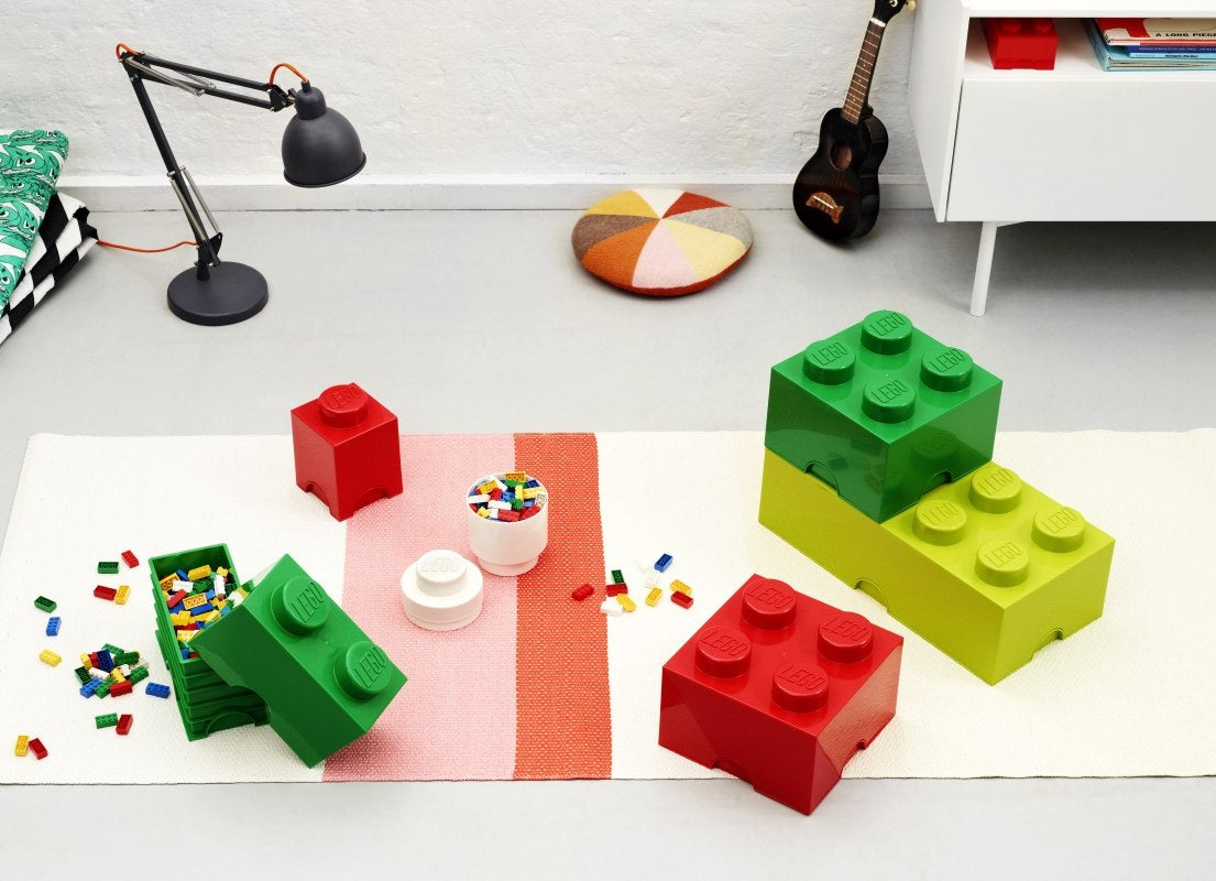 Zielony pojemnik LEGO Brick 4 do przechowywania klocków na jasnym dywanie w pokoju