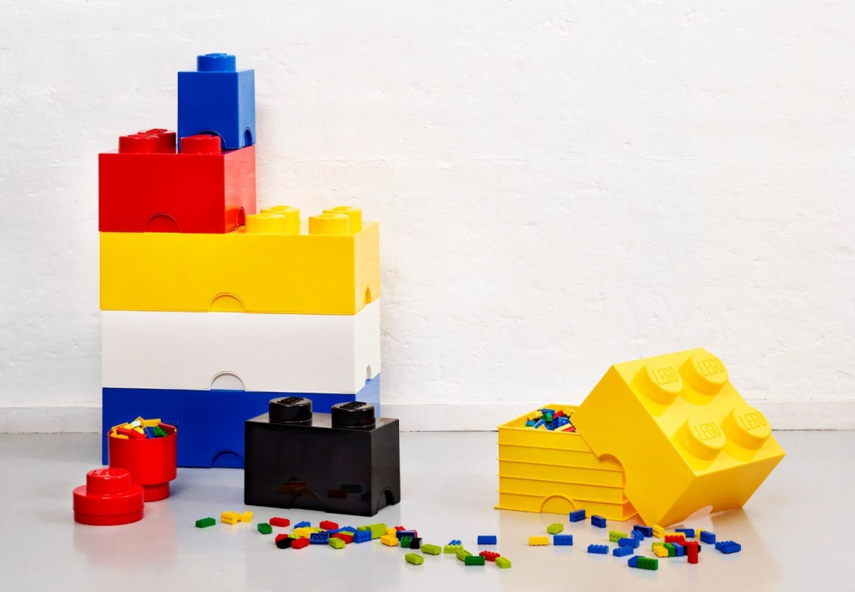 Kolorowy pojemnik LEGO na zabawki w kształcie klocków z rozrzuconymi klockami na podłodze