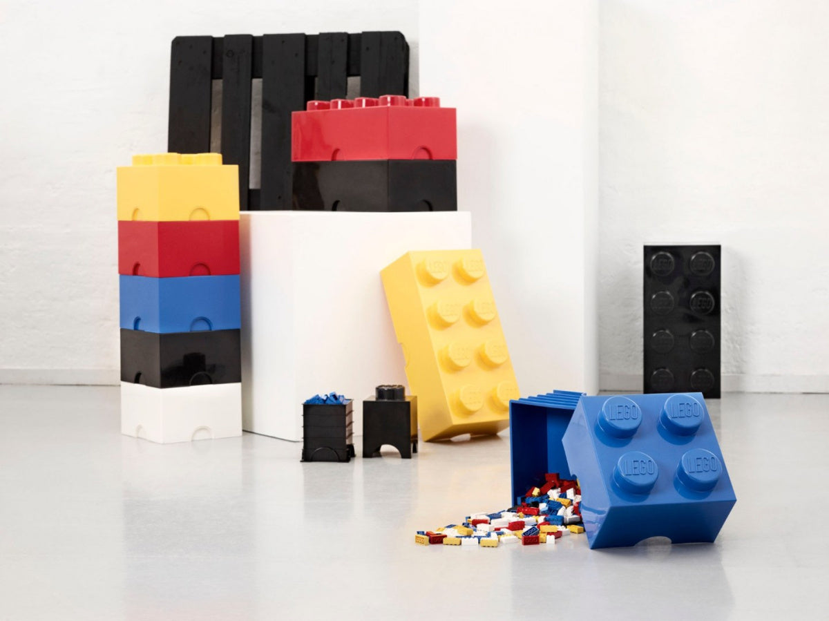 Pojemnik LEGO Brick 4 niebieski z rozsypanymi drobnymi klockami LEGO na podłodze w nowoczesnym wnętrzu